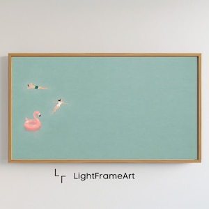 Op de afbeelding: Een ingelijste kunstdruk met een serene scène van drie figuren die zwemmen in een turquoise watermassa. Een roze flamingo-drijver staat op de voorgrond. Het kunstwerk is ingelijst in een lichtbruine houten lijst. De tekst "LightFrameArt" staat rechtsonder.
