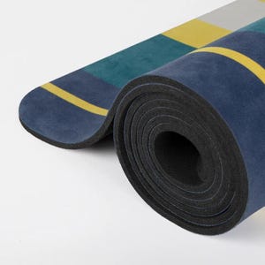 May include: A rolled up yoga mat with a blue, green and yellow striped pattern. The mat is made of a thick, durable material and is perfect for yoga, Pilates or stretching.