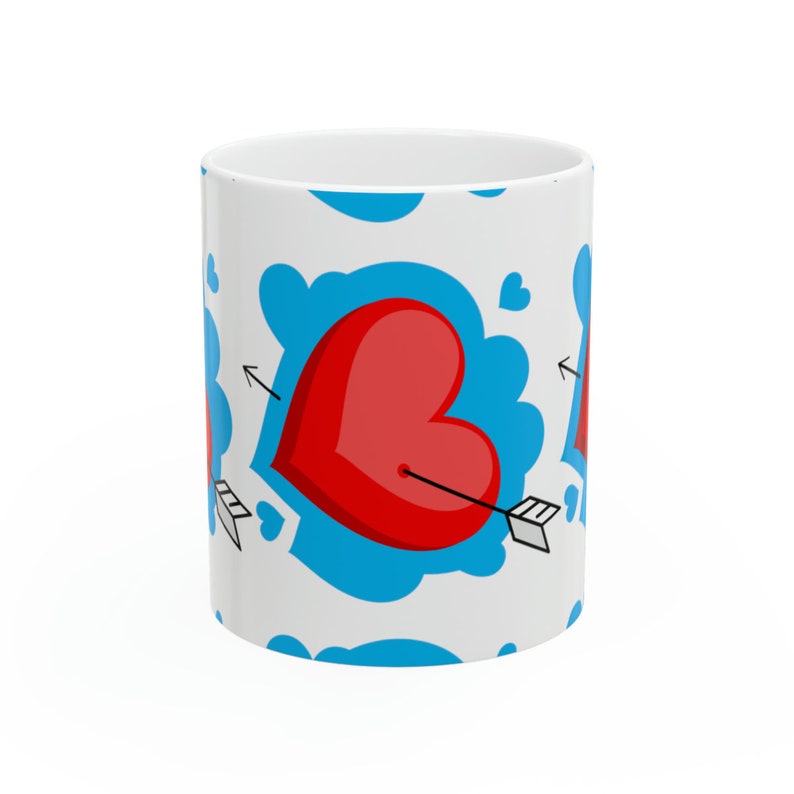 May include: White ceramic mug with a repeating pattern of red hearts with arrows through them, surrounded by blue clouds.