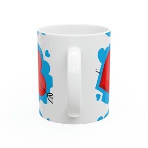 May include: White ceramic mug featuring a blue and red heart design. The hearts are surrounded by blue clouds and have arrows through them.