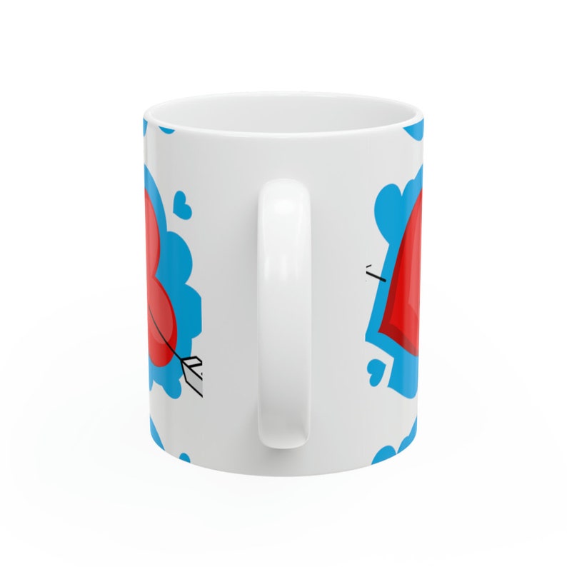May include: White ceramic mug featuring a blue and red heart design. The hearts are surrounded by blue clouds and have arrows through them.