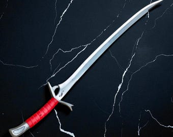 May include: A silver sword with a curved blade and a red wrapped handle. The sword has a decorative hilt and a pointed tip. The blade is reflective, and the handle is a vibrant red color.