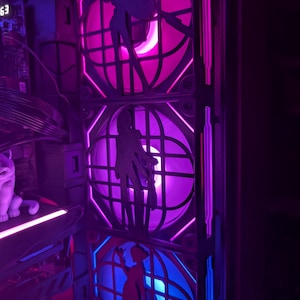 Puede incluir: Una caja de ordenador con tres ventiladores iluminados. Cada ventilador tiene una silueta y está iluminado con luces rosas, moradas y azules. La caja tiene una estética oscura y futurista.