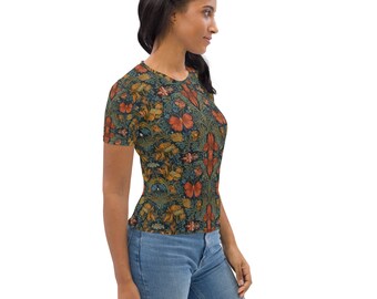 May include: A woman wearing a short-sleeved t-shirt with a floral print. The shirt has a dark blue background with orange, red, and yellow flowers. The woman is wearing blue jeans.