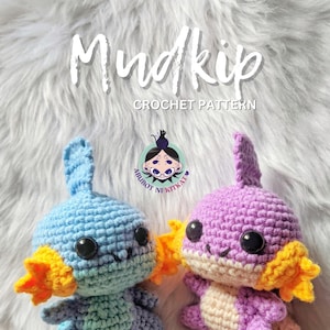 Pode incluir: Duas figuras de Mudkip de crochê, uma azul e outra roxa, com detalhes em laranja. As figuras têm olhos grandes e pretos e estão sorrindo. A imagem inclui o texto "Mudkip CROCHET PATTERN" e o logotipo "ABUBOT NI KITKAT".