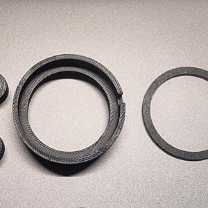 May include: Three black plastic rings of different sizes. The largest ring is a double ring with a slightly raised edge. The smallest ring is a solid ring. The middle ring is a single ring with a slightly raised edge.