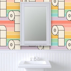 May include: A bathroom scene featuring a white framed mirror above a white sink. The wallpaper has a repeating pattern of toilet paper rolls against a rainbow striped background. The sink has a chrome faucet.