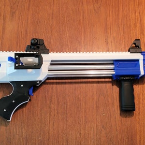 May include: A white and blue toy gun with a black handle and orange tip. The toy gun has a long barrel and a sight on top. The gun is made of plastic and has a detailed design.