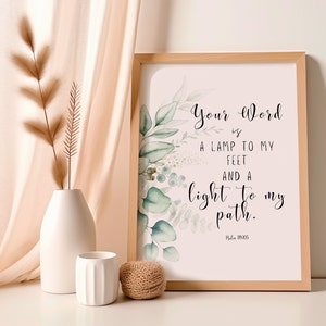 May include: A framed print with the text "Your Word is a lamp to my feet and a light to my path." The print is decorated with watercolor eucalyptus leaves. A white vase with dried plants, a small white cup, and a ball of twine are in the foreground.