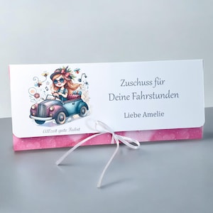 Könnte beinhalten: Eine Geschenkkarte mit einer Aquarellillustration einer Person, die ein Oldtimer fährt. Die Karte trägt den Text "Zuschuss für Deine Fahrstunden Liebe Amelie" und "Allzeit gute Fahrt". Die Karte ist weiß mit einem rosa gemusterten Rand und einem weißen Band.