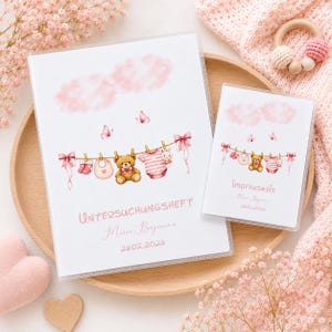 Könnte beinhalten: Zwei weiße Baby-Aufnahmebücher mit rosa Wolken- und Wäscheleinen-Designs. Das größere Buch trägt den Text "UNTERSUCHUNGSHEFT" sowie einen Namen und ein Datum. Das kleinere Buch trägt "Impfausweis" und ein Datum.