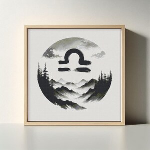 May include: Square framed artwork featuring a Libra zodiac symbol in black. The symbol is set against a circular backdrop of a mountain landscape in shades of gray and green, with a light wood frame.