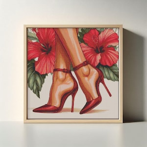 May include: A framed artwork featuring a pair of legs wearing red high-heeled shoes with ankle straps. Large red hibiscus flowers and green leaves are in the background. The artwork is in a light-colored wooden frame.