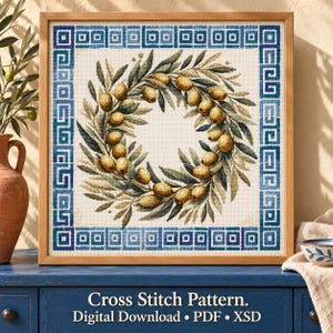 Puede incluir: Un patrón de punto de cruz enmarcado con una corona central de hojas de olivo verdes y aceitunas amarillas, rodeado por un borde geométrico azul y blanco. El texto dice: Cross Stitch Pattern. Digital Download • PDF • XSD.