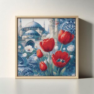 May include: A framed art print featuring a vibrant floral arrangement of red tulips and white flowers against a backdrop of a blue-domed building and ornate blue and white pottery. The artwork is set in a light-colored wooden frame.