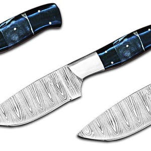 Könnte beinhalten: Drei Messer aus Damaszenerstahl mit dunkelblauen und weißen Griffen. Die Klingen haben ein ausgeprägtes Holzmaserungsmuster. Die Griffe sind dunkelblau mit weißen Akzenten. Die Messer sind in verschiedenen Winkeln angeordnet.