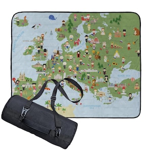 Könnte beinhalten: Eine zusammengerollte schwarze Picknickdecke mit Schultergurt neben einer grünen Decke. Die grüne Decke zeigt eine Karte von Europa mit Cartoon-Illustrationen von Sehenswürdigkeiten und Menschen. Das Atlantik und Schwarze Meer sind beschriftet.