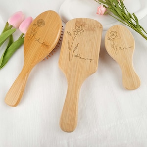 May include: Three wooden hairbrushes with engraved floral designs and names. The brushes are in different shapes and sizes, with the names "Andre", "Henry", and "Carrie" etched on them. The brushes are made of light-coloured wood.