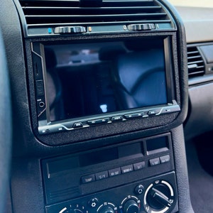 Könnte beinhalten: Ein schwarzes Armaturenbrett mit einem Touchscreen-Radiodisplay, Knöpfen zur Temperaturregelung und einem Drehknopf zum Einstellen der Lautstärke.