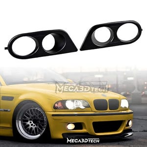 May include: Two black car headlight bezels with circular openings. The bezels are angled and designed to fit a yellow car, with the brand name "MECA3DTECH" visible on the car.