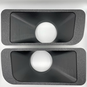 以下が含まれることがあります： スピーカー用の円形カットアウトが付いた、黒いフォーム製のスピーカーサラウンドが2つ。サラウンドは長方形で、わずかにテクスチャ加工された表面をしています。