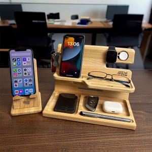 Può includere: Un supporto per telefono in legno con un telefono, un orologio, chiavi, occhiali, una penna, una chiave per auto e una piccola custodia bianca. Il supporto è in legno chiaro e ha una finitura naturale. Il supporto ha un piccolo cartello che dice "Wood Rider".