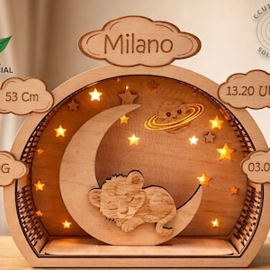 May include: Wooden night light with a lion cub on a crescent moon, stars, and a planet. The name "Milano" is above the moon. Includes measurements: 53 cm, 3550g, and the date 03.04.2025. The time is 13.20.
