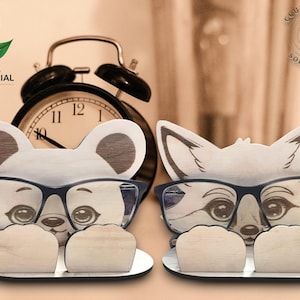 May include: Two wooden eyeglass holders, one shaped like a bear and the other a fox, both wearing glasses. They sit on a small, white tray. A black alarm clock is in the background. The image includes the text "INCLUDING COMMERCIAL LICENSE".