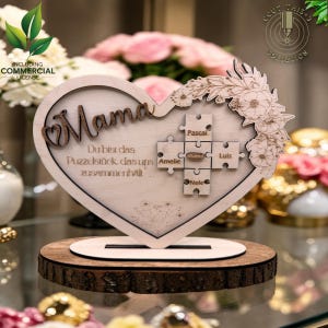 May include: Wooden heart-shaped plaque with the word "Mama" and a floral design. It features puzzle pieces with names and the phrase "Du bist das Puzzelstück das uns zusammenhält."