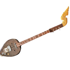 Puede incluir: Una guitarra eléctrica marrón única con un cuerpo en forma de hoja y un mástil largo. El clavijero está intrincadamente tallado con un diseño dorado. El instrumento presenta múltiples perillas y pastillas, y un diapasón con incrustaciones blancas.