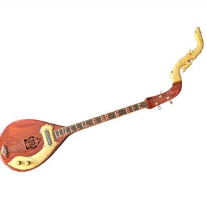 Puede incluir: Un Phin de madera, un laúd tradicional tailandés, con un cuerpo en forma de lágrima y un mástil largo. El instrumento presenta intrincadas tallas en el clavijero y una boca decorativa. El cuerpo es de color marrón intenso, con detalles dorados.