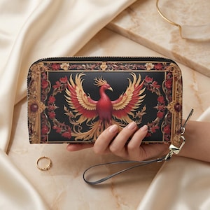 May include: Black wallet with a phoenix design. The phoenix is red and gold, with outstretched wings, set against a black background with floral accents. The wallet has a wrist strap and a gold-colored zipper.