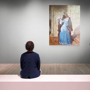 Puede incluir: Interior de una galer&iacute;a de arte con una persona sentada en un banco blanco, mirando una pintura. La pintura muestra a una mujer con un vestido azul y un hombre abraz&aacute;ndose. Las paredes son grises y el suelo es de madera.