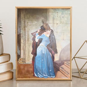 Puede incluir: Una pintura enmarcada representa a una pareja abraz&aacute;ndose, ambientada en una arquitectura de piedra. La mujer viste un largo vestido azul fluido, mientras que el hombre est&aacute; envuelto en ropa oscura. La obra de arte est&aacute; enmarcada en oro.