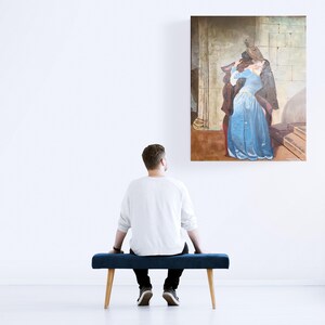 Puede incluir: Una pintura enmarcada que representa a una mujer con un vestido azul y un hombre con un abrigo oscuro. La obra de arte se exhibe en una pared blanca sobre un banco azul. Una persona est&aacute; sentada en el banco, mirando la pintura.