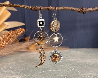 Könnte beinhalten: Ohrringe mit Himmelsmotiven, die Sonne, Mond und Stern-Anhänger zeigen. Die Ohrringe sind in Silber- und Goldtönen gehalten und weisen detaillierte Anhänger auf. Die Sonne hat ein lächelndes Gesicht, und der Mond ist halbmondförmig.