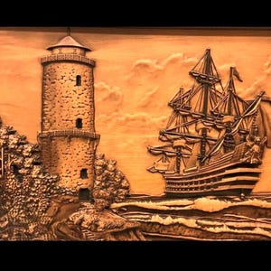 Puede incluir: Una detallada talla de madera que representa una escena costera. Un alto faro se alza a la izquierda, con un velero a la derecha. La talla es en tonos marrones, con intrincados detalles de las velas del barco y la mampostería del faro.