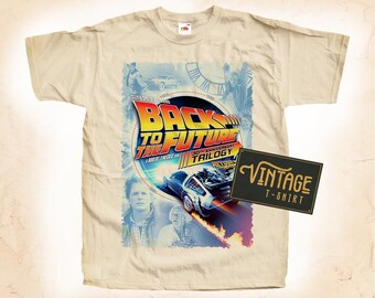 May include: A beige t-shirt with a vintage Back to the Future 30th Anniversary Trilogy design. The design features the DeLorean time machine, Marty McFly, and Doc Brown. The text "Back to the Future 30th Anniversary Trilogy" is printed in bold, colorful letters. The t-shirt has a vintage look and feel.