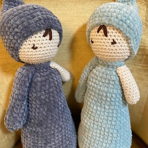 Puede incluir: Dos muñecas hechas a mano con ganchillo. Una muñeca es azul oscuro, la otra azul claro. Ambas muñecas tienen una cara, brazos y un gorro puntiagudo blancos. Las muñecas tienen ojos y cejas cosidos en marrón. Las muñecas están hechas de hilo suave y texturizado.