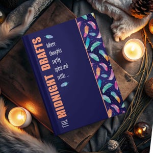 May include: A dark blue hardcover journal featuring the text "THE MIDNIGHT DRAFTS Where thoughts softly spiral and settle..." in light orange. The right side displays a vertical panel with a pattern of colorful feathers on a dark background.