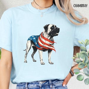 May include: Light blue t-shirt with a graphic of a bulldog wearing a red, white, and blue bandana. The bandana is patterned like the American flag. The text "CHAMBRAY" is in the top right corner of the image.