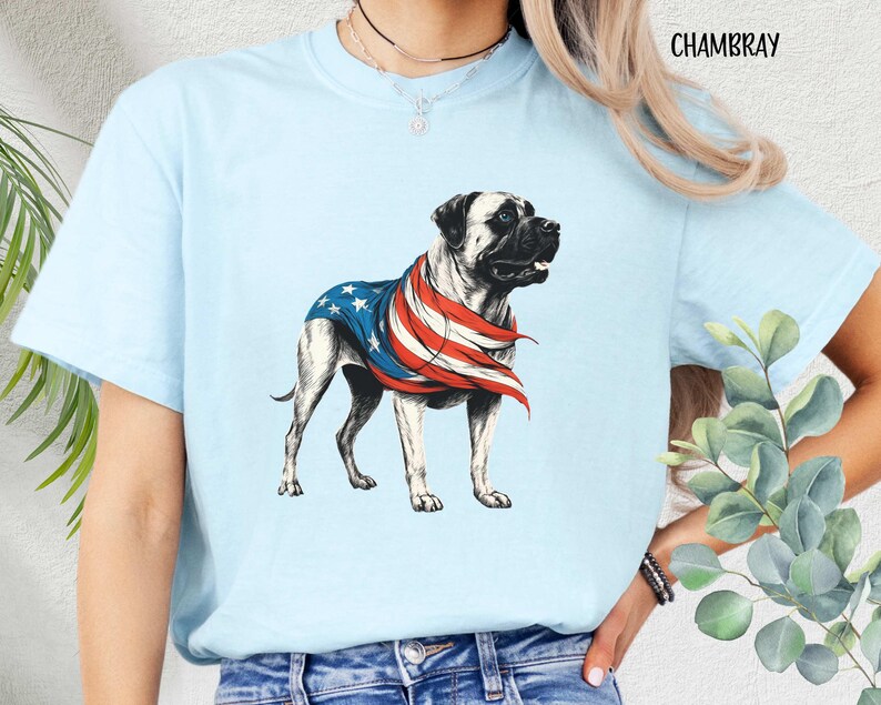 May include: Light blue t-shirt with a graphic of a bulldog wearing a red, white, and blue bandana. The bandana is patterned like the American flag. The text "CHAMBRAY" is in the top right corner of the image.