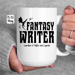 May include: White 15 oz mug with the words "FANTASY WRITER" in bold black letters, a dragon silhouette, and the text "Guardian of Myths and Legends." The mug is held by a person.
