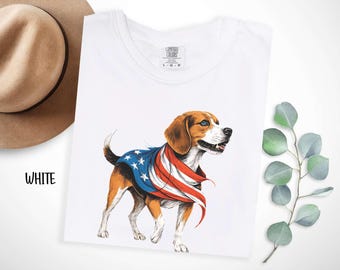 Op de afbeelding: Wit T-shirt met een afbeelding van een beagle die een rood-wit-blauw Amerikaans vlag bandana draagt. De tekst "COMFORT COLORS" is op het shirt gedrukt.