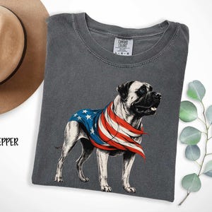 May include: A gray t-shirt with a graphic of a Bullmastiff dog wearing a red, white, and blue American flag bandana. The text "COMFORT COLORS" is on the tag.