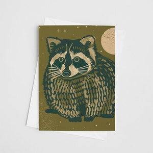 May include: A green and gold illustrated card featuring a raccoon with a black mask and a full, round body. The raccoon is standing in front of a full moon and stars.