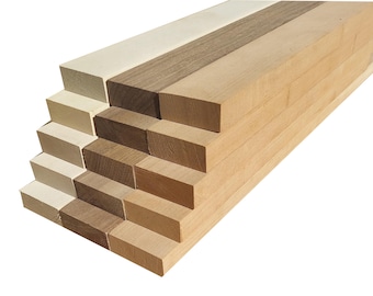 Puede incluir: Tablas de madera apiladas en varios tonos de marrón, beige y blanco. Las tablas están dispuestas en forma escalonada, creando una forma piramidal visual.
