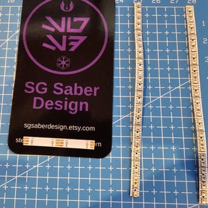 May include: Two strips of silver-coloured LED lights with a black background behind them. The background has the text "SG Saber Design" and a website address. The LED strips are numbered 1 through 10.