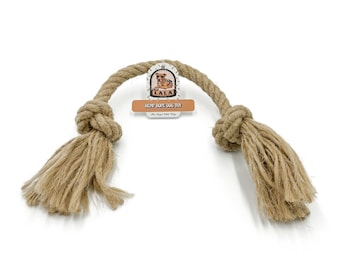 May include: A natural hemp rope dog toy with a knotted center and frayed ends. The toy has a tag that reads "LALA HEMP ROPE DOG TOY". The rope is tan and the tag has a dog illustration.