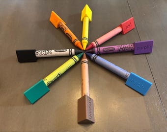 May include: A set of eight jumbo crayons in different colors, including red, yellow, green, blue, purple, brown, and orange. Each crayon has a label that says "Jumbo Crayons" and the color of the crayon. The crayons are arranged in a star shape on a wooden table.